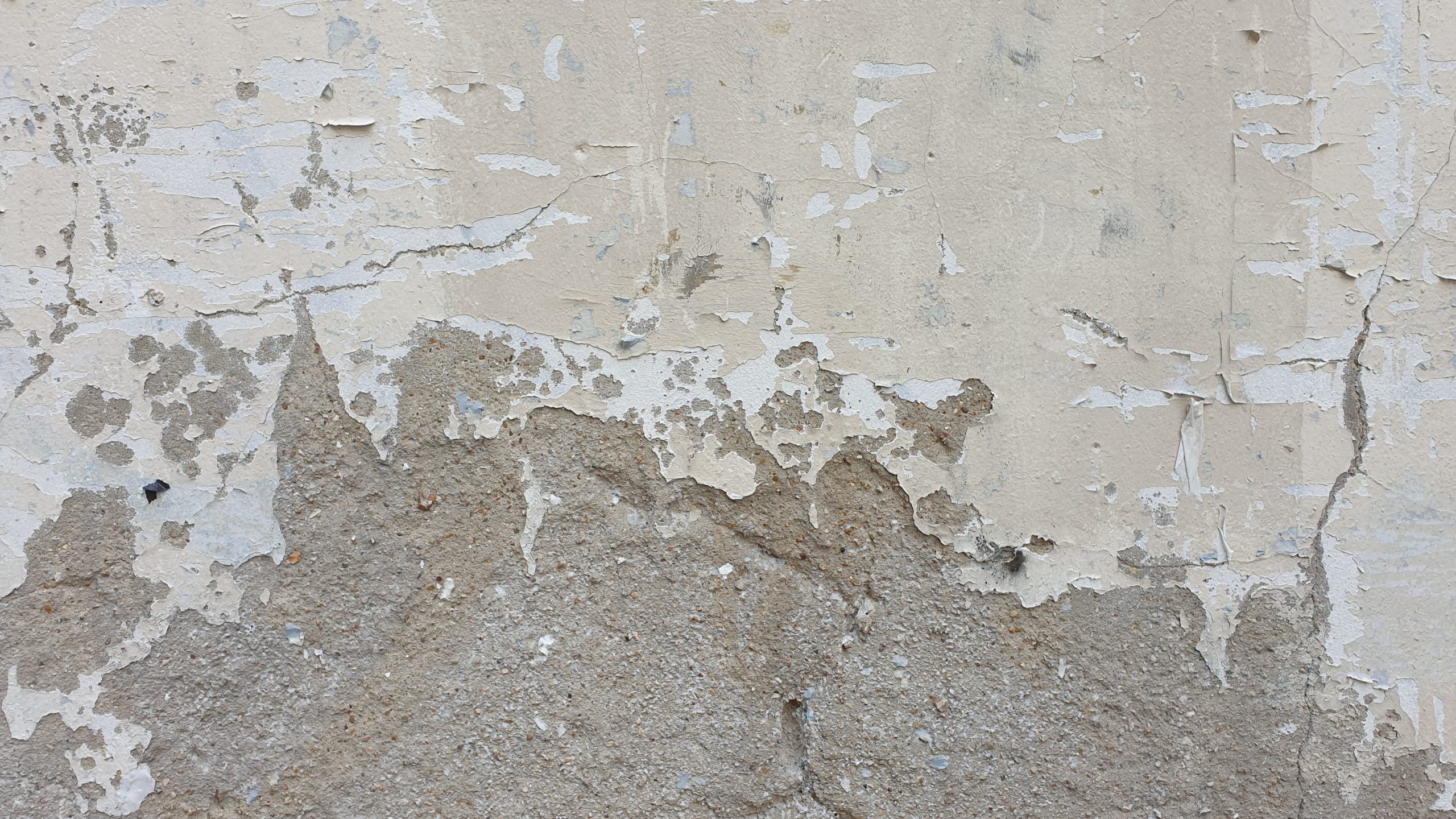 De witte verf komt los van de muur door vochtproblemen.