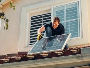 Een man plaatst zonnepanelen op zijn dak