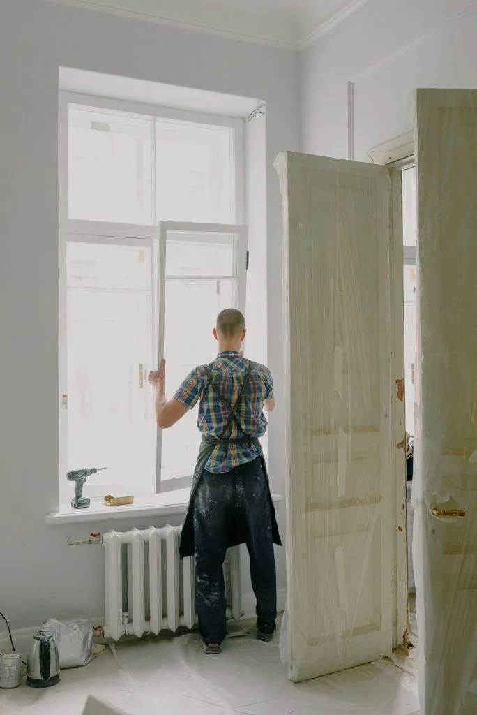 Een klusjesman voert herstellingswerken uit aan de ramen.