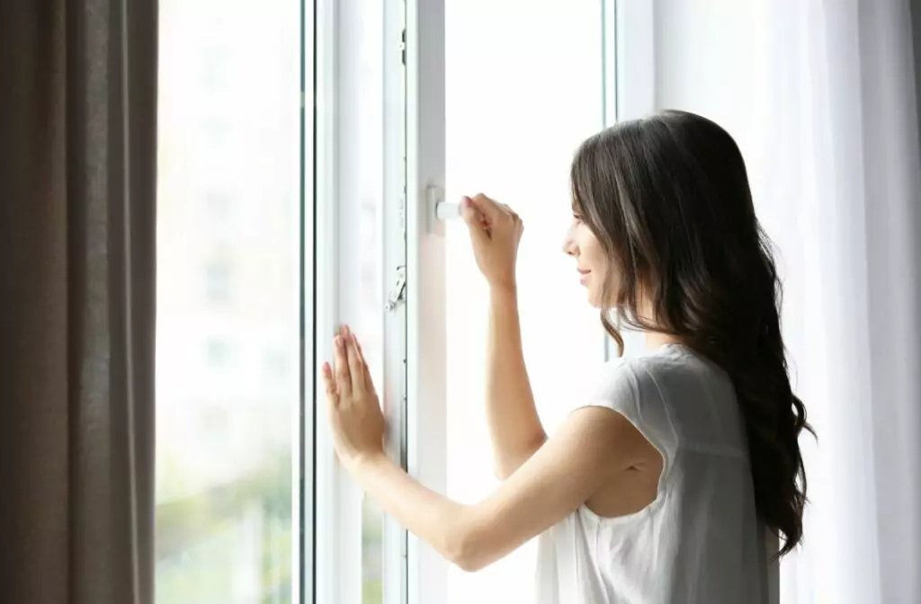 Vrouw dat een raam dicht doet van een warme slaapkamer